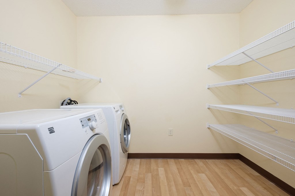 a laundry room with a washer and dryer and shelves. Fargo, ND Crossroads Apartments