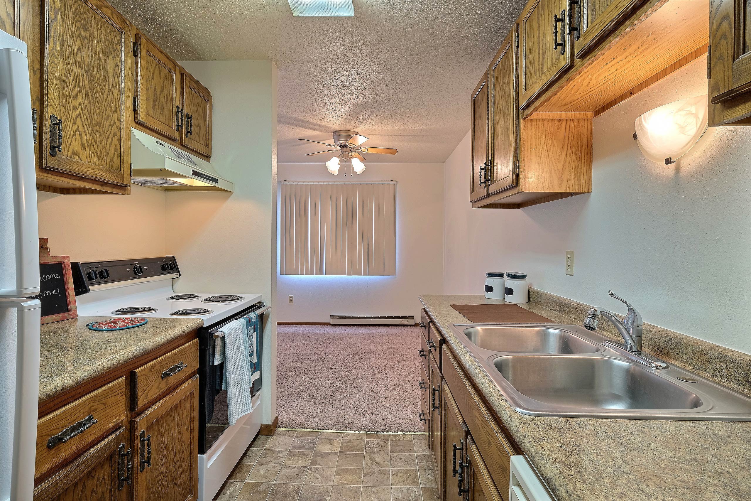a kitchen with white appliances and wooden cabinets. Fargo, ND Pacific South Apartments