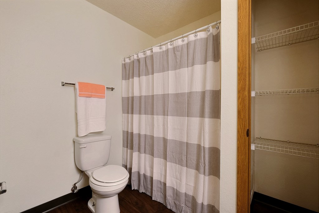 Bathroom with a toilet and a shower curtain  at Park Place Apartments in Fargo, 58103