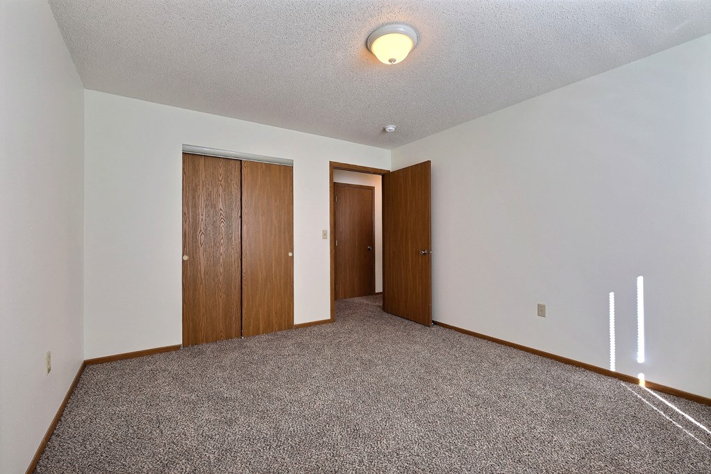 Empty living room with carpet and two doors to a closet  at Park Place Apartments in Fargo, ND