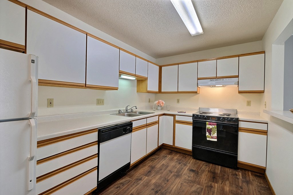 a kitchen with white cabinets and black appliances. Fargo, ND Park Place Apartments