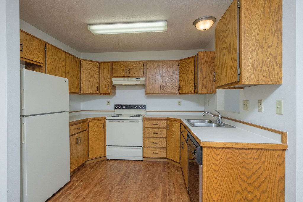 a kitchen with white appliances and wooden cabinets. Fargo, ND Park Circle Apartments.