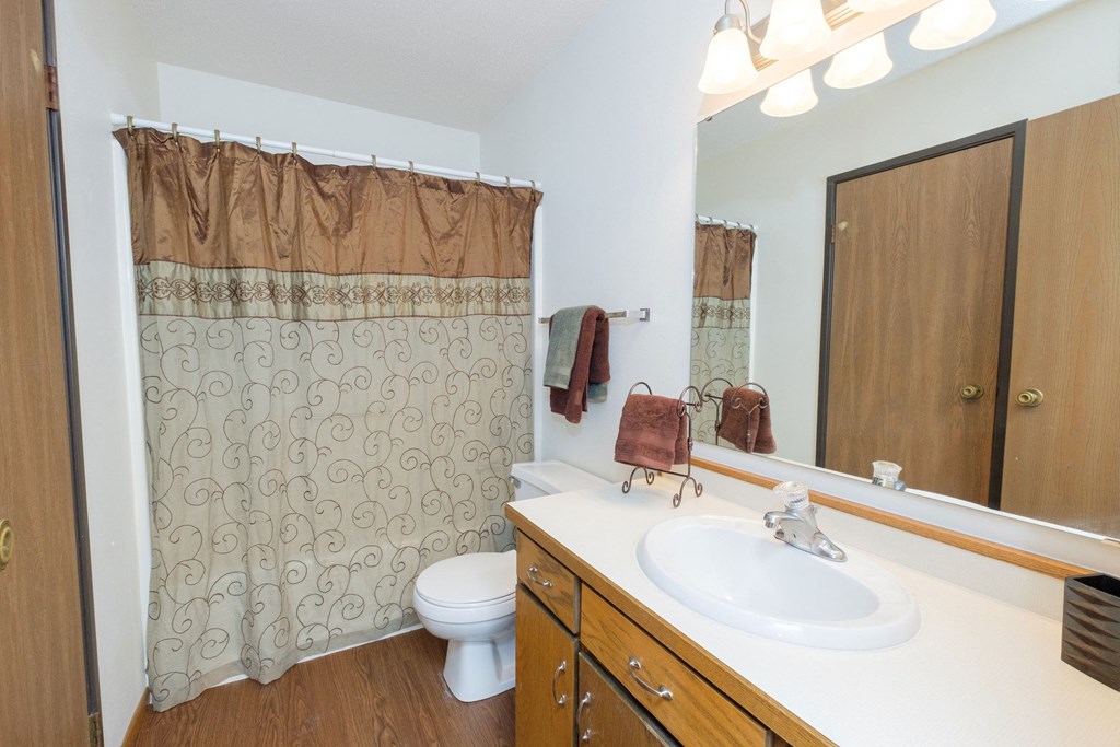 a bathroom with a sink and a toilet and a shower. Fargo, ND Park Circle Apartments.