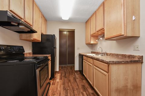 a kitchen with wood cabinets and black appliances  Parkview Estates | Coon Rapids, MN