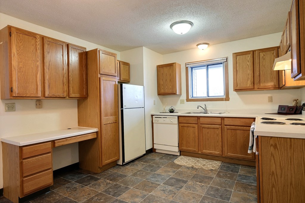 Kitchen with wooden cabinets and a white refrigerator at Parkwest Gardens West Fargo, ND 58078