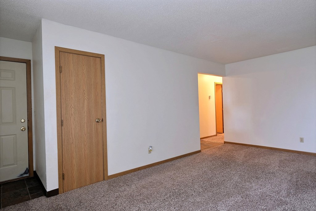 A living room of an empty apartment with a door to the hallway at Parkwest Gardens, 58078