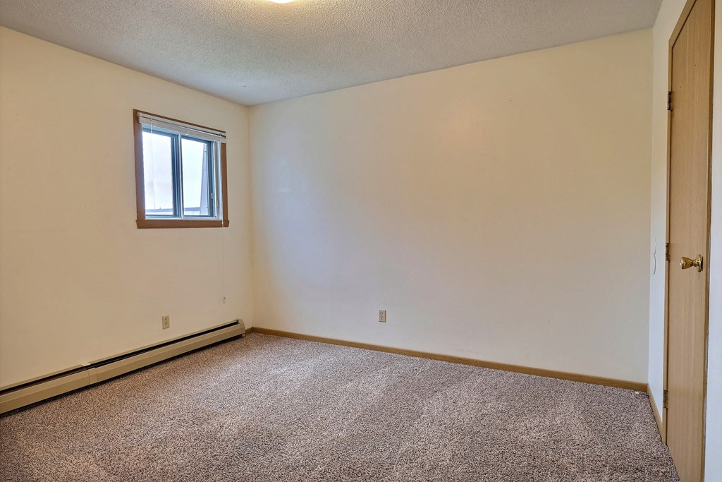 Bedroom with carpeted floors and a window at Parkwest Gardens West Fargo