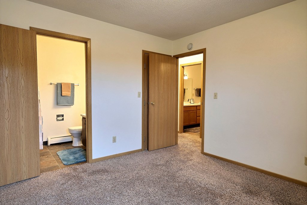 Bedroom with a bathroom attached and a closet at Parkwest Gardens West Fargo