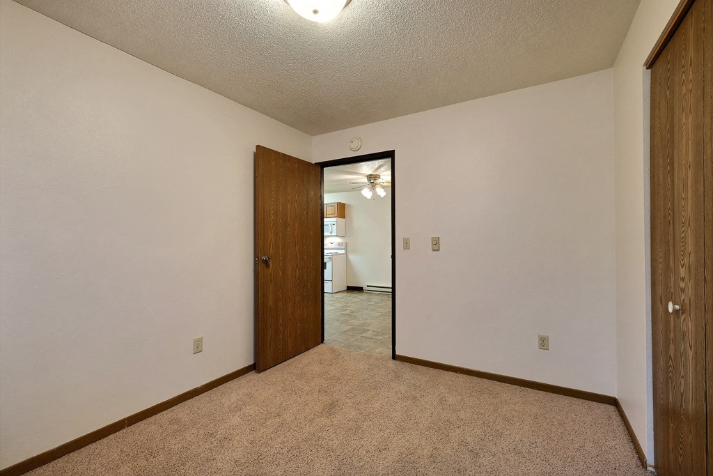 a bedroom with a door to a kitchen.Fargo, ND Prairiewood Courts Apartments