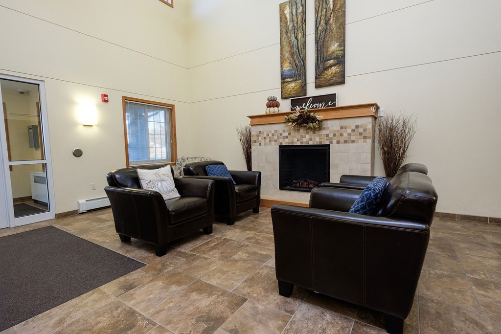 an entrance with four chairs and a fireplace in front of the entry door. Fargo, ND Crossroads Apartments