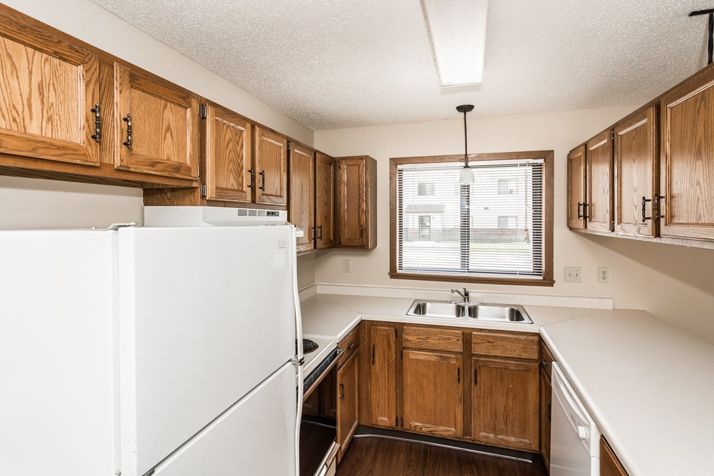 Grand Forks, ND Richfield Apartments. A kitchen with white appliances and wooden cabinets