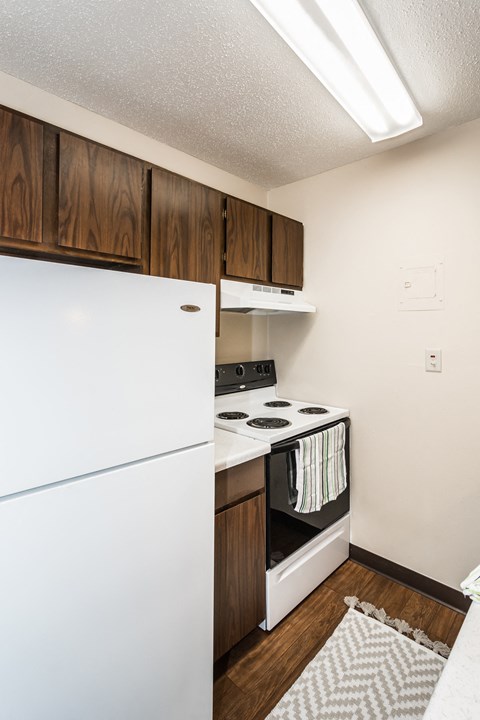 a kitchen with white appliances and wooden cabinets and a refrigerator