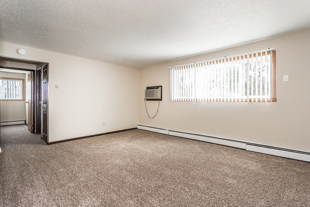 Grand Forks, ND Riverwood Apartments. A living room with carpet and a window
