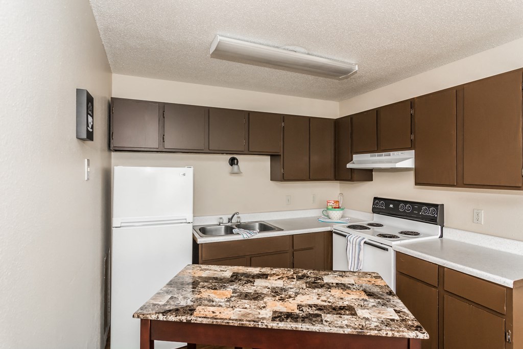 Grand Forks, ND Riverwood Apartments. A kitchen with white appliances and brown cabinets and granite counter tops