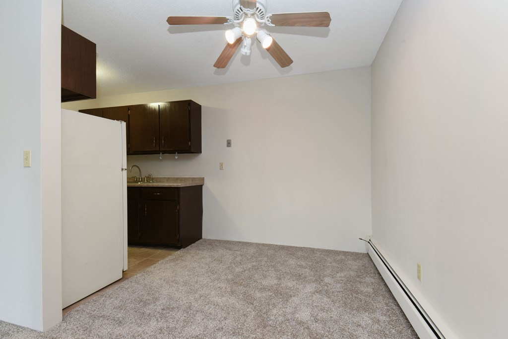 an empty living room with a ceiling fan and a kitchen. Roseville, MN Rosedale Estates