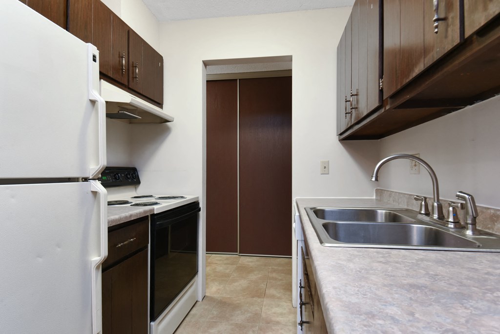 a kitchen with a sink and a refrigerator and a door. Roseville, MN Rosedale Estates