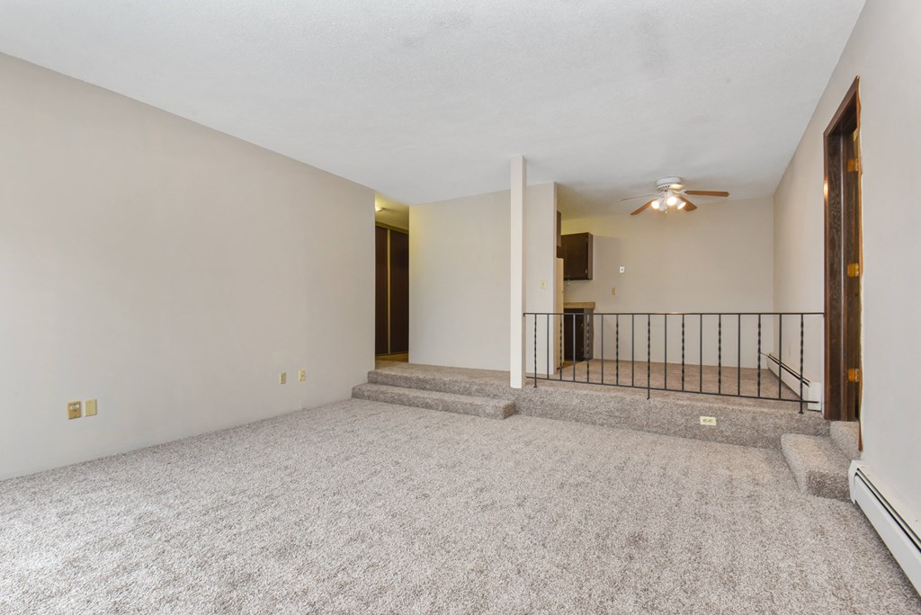 the living room of an empty house with carpet and a ceiling fan. Roseville, MN Rosedale Estates
