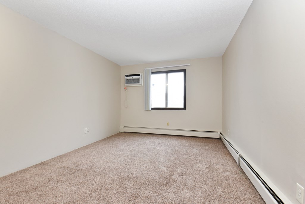 an empty living room with carpet and a window. Roseville, MN Rosedale Estates