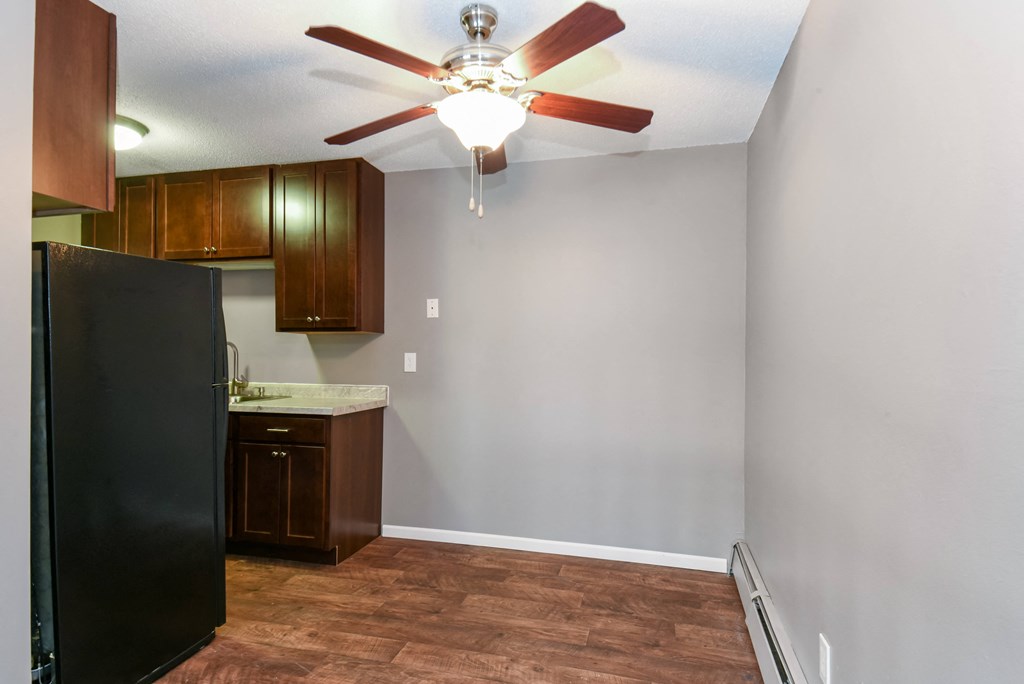 an empty kitchen with a ceiling fan and a refrigerator. Roseville, MN Rosedale Estates