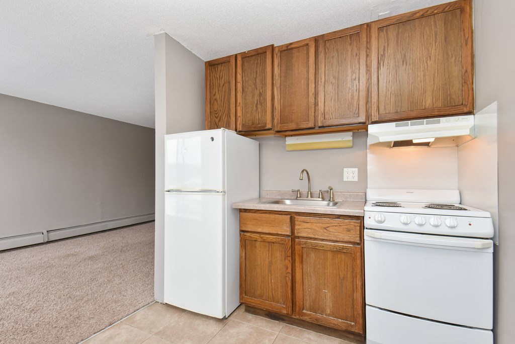 an empty kitchen with white appliances and wooden cabinets. Roseville, MN Rosedale Estates