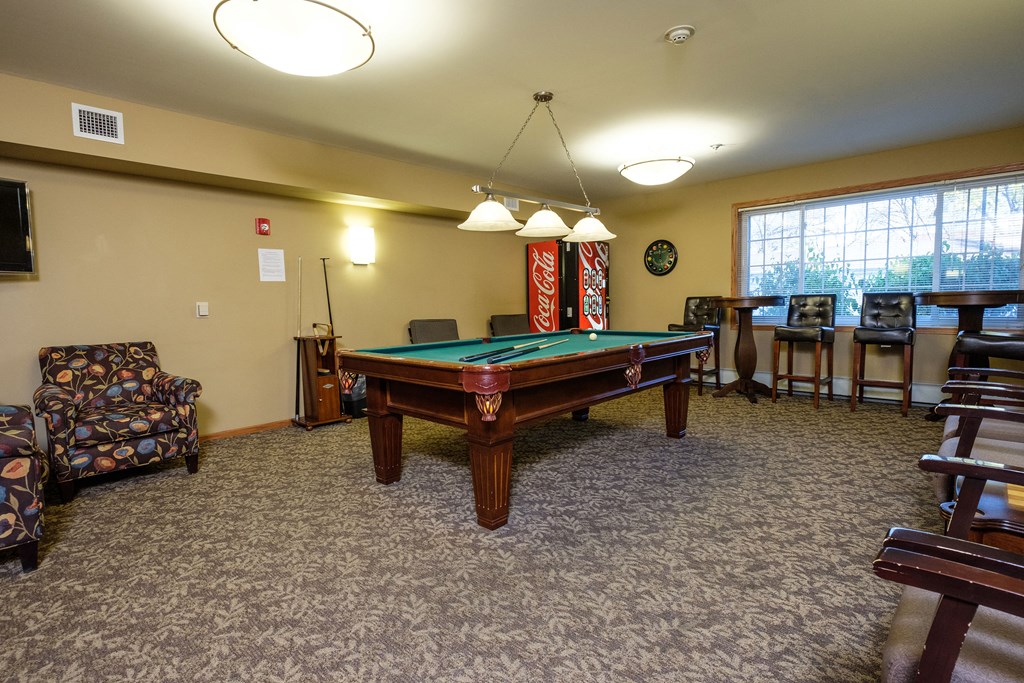 a pool table with chairs around it and a window. Fargo, ND Crossroads Apartments