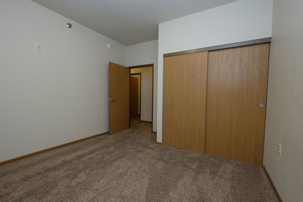 a bedroom with a door to a hallway and a closet. Fargo, ND North Sky Apartments