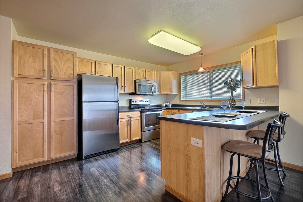 a kitchen with stainless steel appliances and wooden cabinets. Moorhead, MN Sandy Creek Apartments
