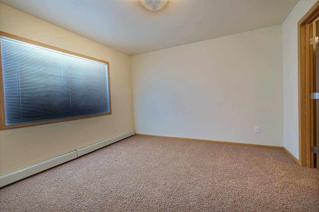 a bedroom with a window and carpet. Moorhead, MN Sandy Creek Apartments