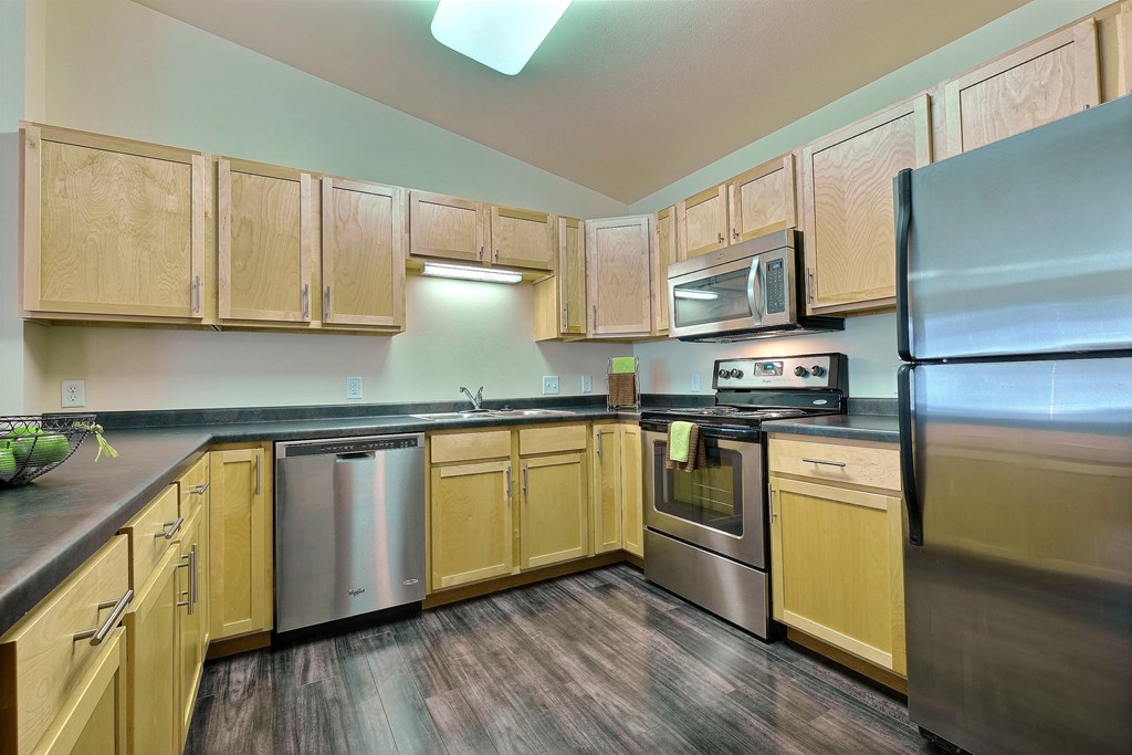 a kitchen with stainless steel appliances and wooden cabinets. Moorhead, MN Sandy Creek Apartments