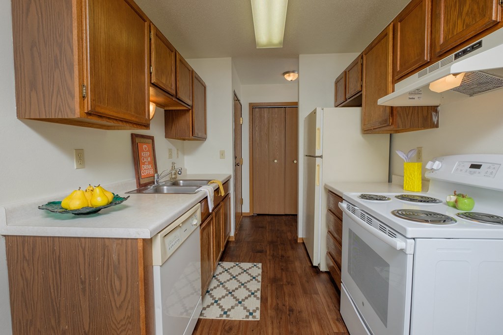 a kitchen with white appliances and wooden cabinets. Fargo, ND Sargent Apartments