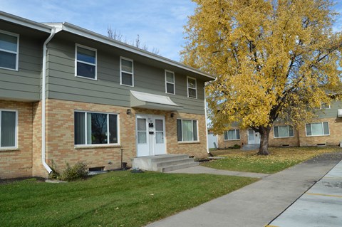 an apartment building with a sidewalk and a tree. Fargo, ND Sheyenne Terrace