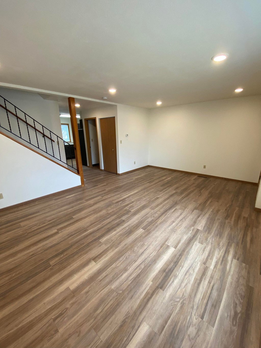 An empty living room with wooden floors and white walls
