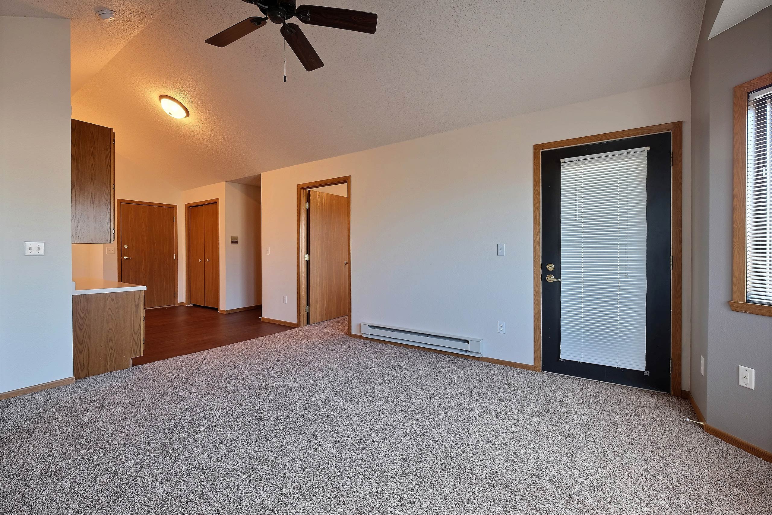 a living room with a patio door and office space in the background. Fargo, ND Somerset Apartments