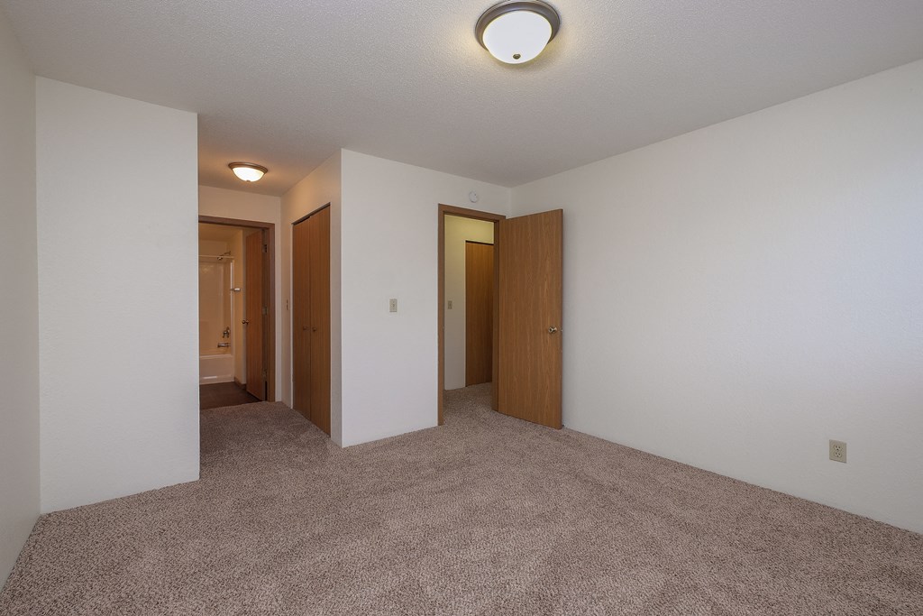a master bedroom with a closet and bathroom attached. Fargo, ND South Pointe Apartments