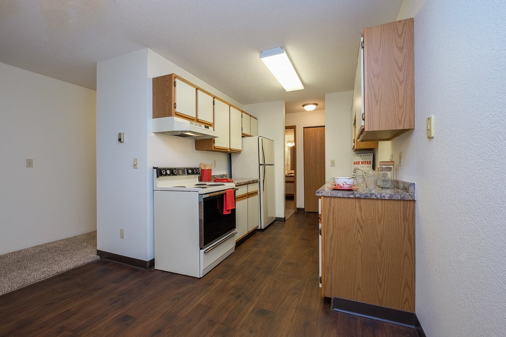 a kitchen with white appliances and wooden cabinets. Fargo, ND South Pointe Apartments