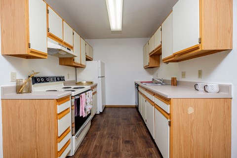 a kitchen with white appliances and wooden cabinets. Fargo, ND South Pointe Apartments