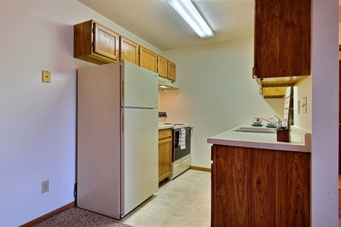 a kitchen with white appliances and wooden cabinets. Fargo, ND Southgate Apartments