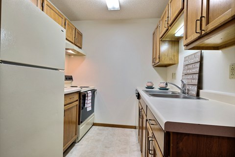 a kitchen with white appliances and wooden cabinets. Fargo, ND Southgate Apartments