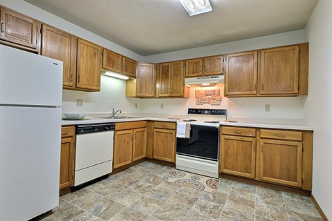 a kitchen with white appliances and wooden cabinets. Fargo, ND Southgate Apartments