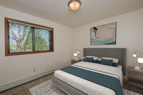a bedroom with a bed and window. Fargo, ND South Pointe Apartments