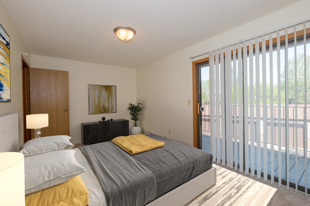 Fargo, ND South Pointe Apartments | Bedroom a bedroom with a bed and glass sliding door to a patio. Fargo, ND South Pointe Apartments