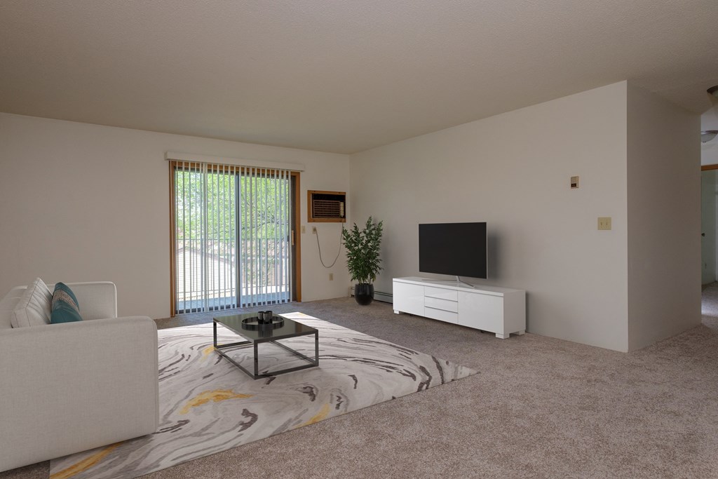 a living room filled with furniture and a flat screen tv with a glass sliding door. Fargo, ND South Pointe Apartments