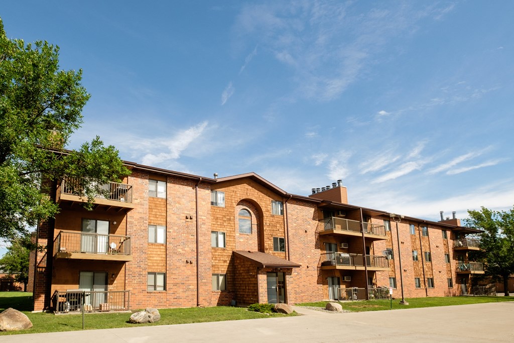 a brick apartment building with balconies and a blue sky. Fargo, ND Southview Village Apartments