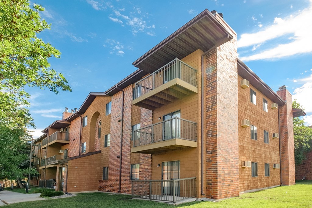 a brick apartment building with balconies and a blue sky. Fargo, ND Southview Village Apartments