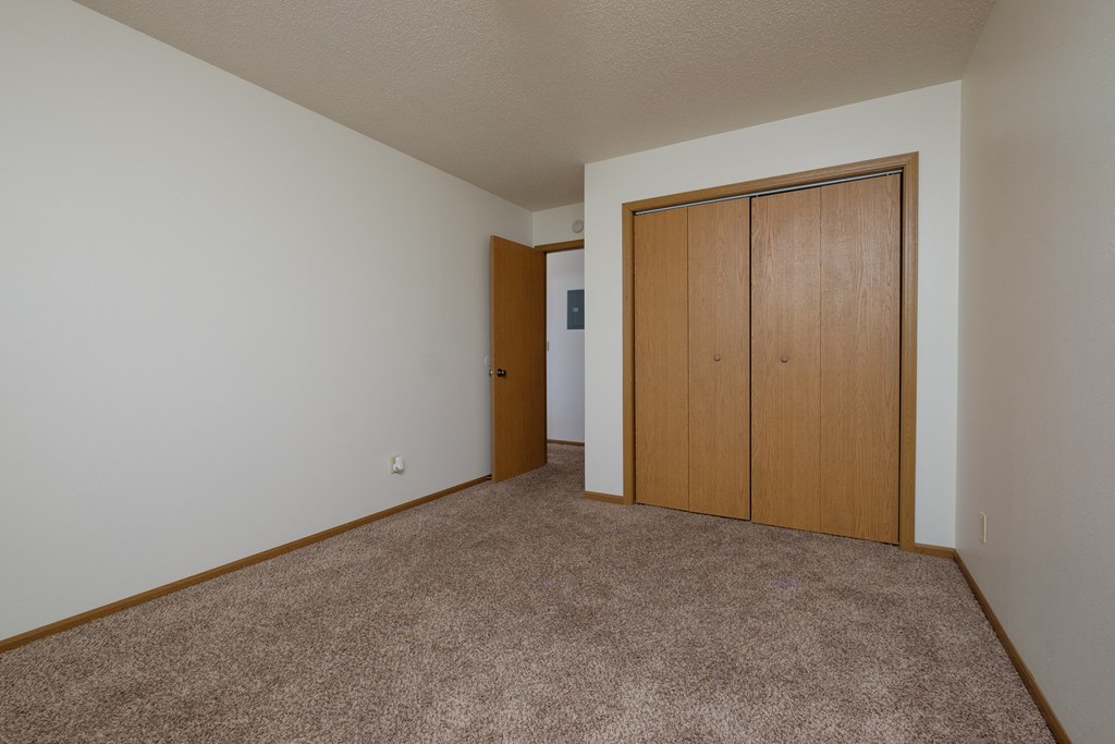 a bedroom with a closet and a door to a hallway. Fargo, ND Southwind Apartments