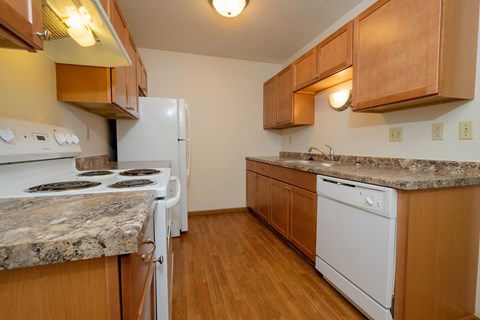 a kitchen with white appliances and wooden cabinets. Fargo, ND Southwind Apartments