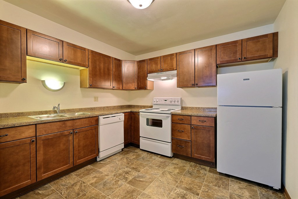 a kitchen with white appliances and wooden cabinets. Fargo, ND Spring Apartments