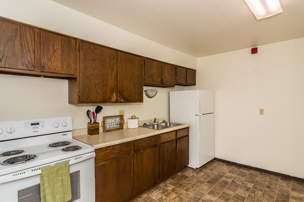 a kitchen with white appliances and wooden cabinets and a white refrigerator. Grand Forks, ND Stanford Court Apartments