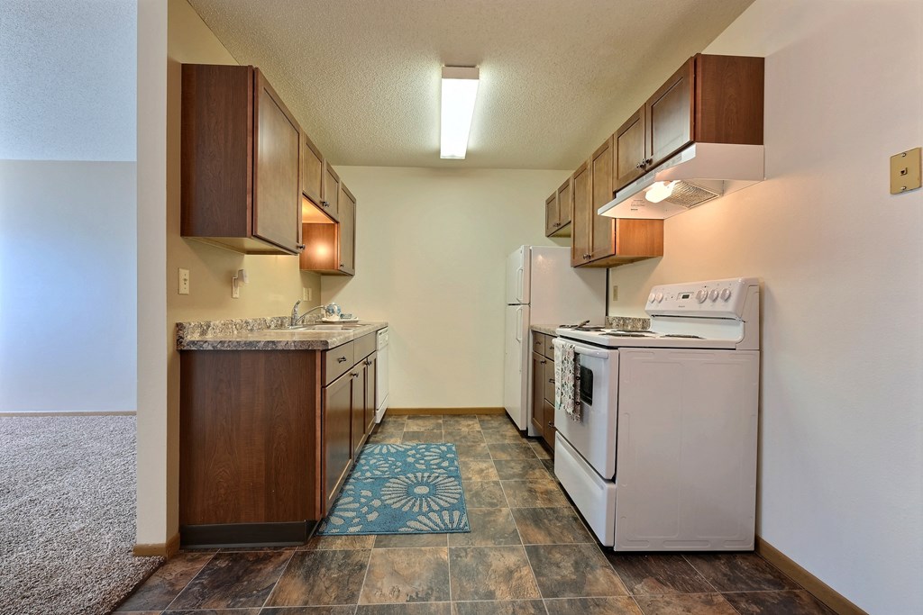 a kitchen with white appliances and wooden cabinets. Fargo, ND Sterling Park Apartments