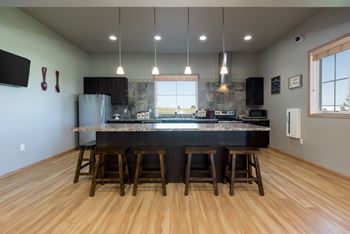 Bismarck, ND Stonefield Apartments. Community room with a kitchen with a large center island with a granite countertop